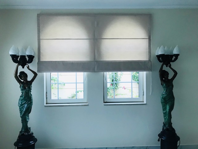 Cream Roman blinds in a decorative room with statue accents